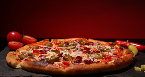 Photo of Delicious pizza Diablo on slate board against red background