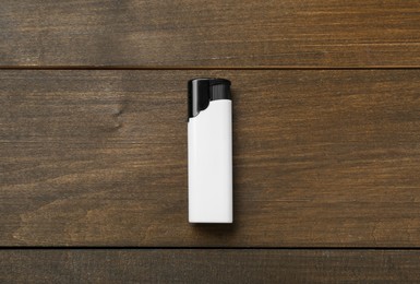 Photo of White plastic cigarette lighter on wooden table, top view