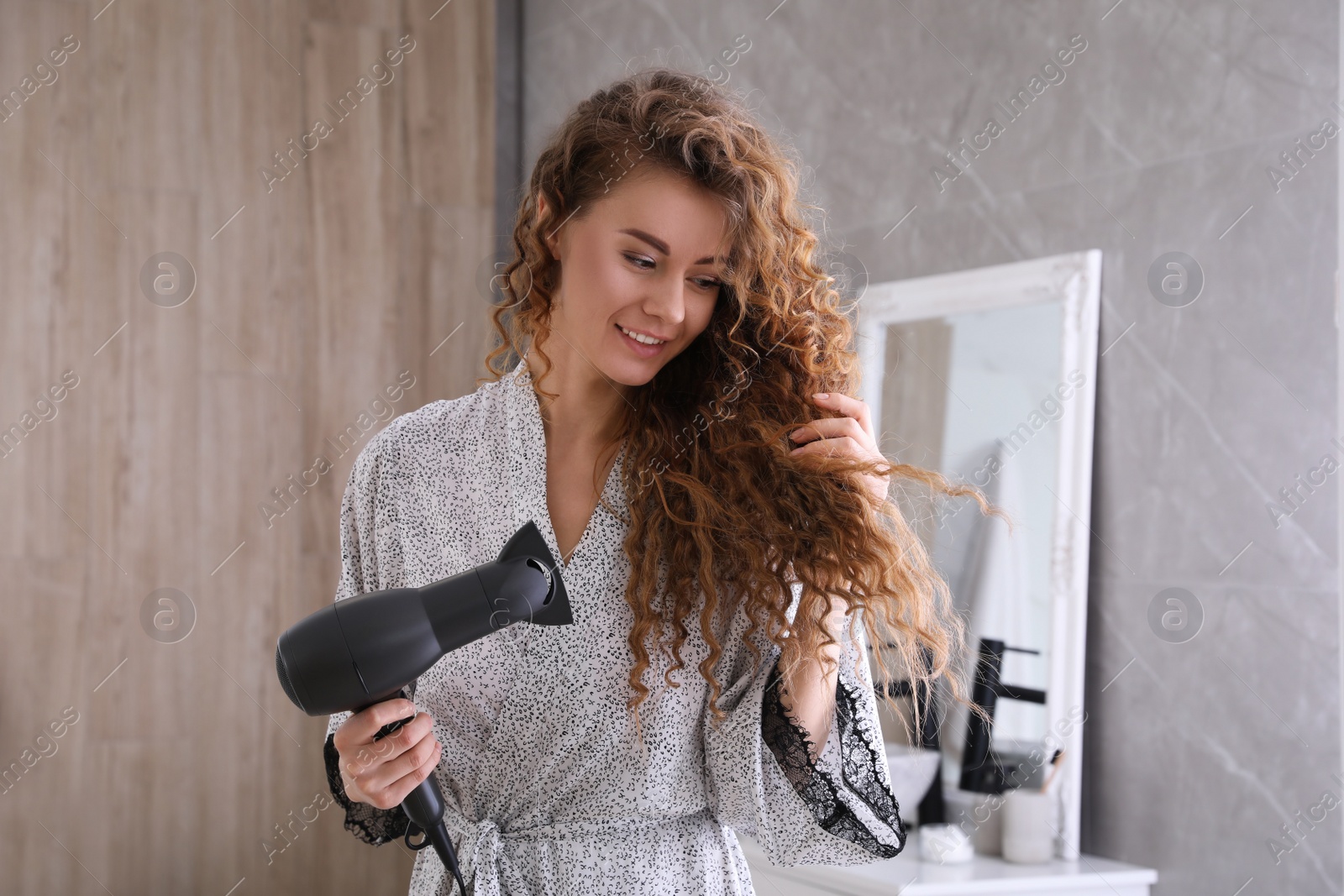 Photo of Beautiful woman using hair dryer in bathroom