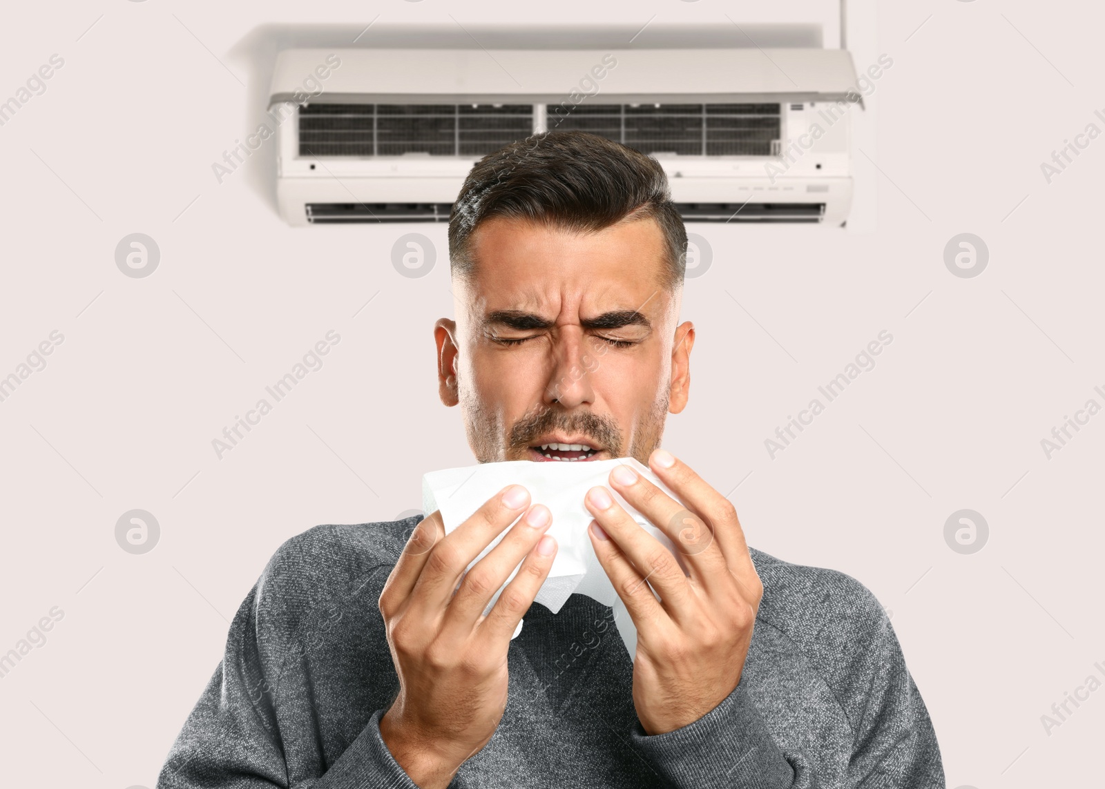 Image of Man suffering from cold in room with air conditioner on white wall