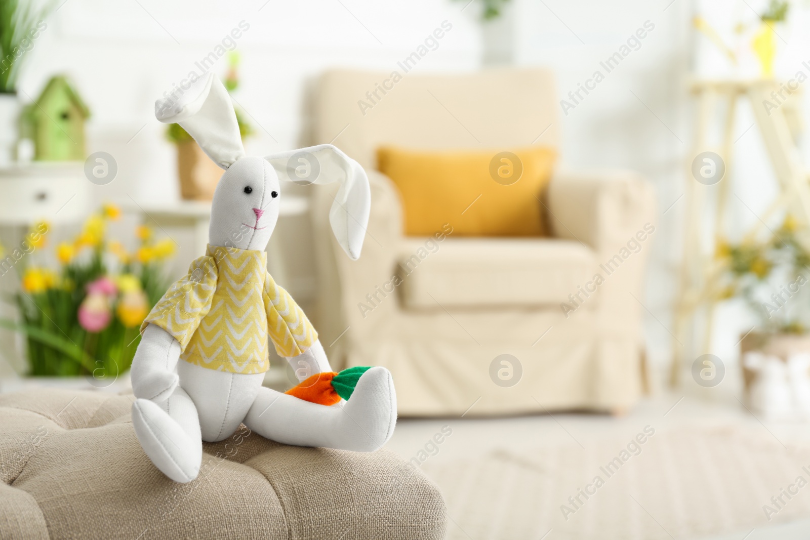 Photo of Cute toy rabbit on bench indoors. Easter photo zone