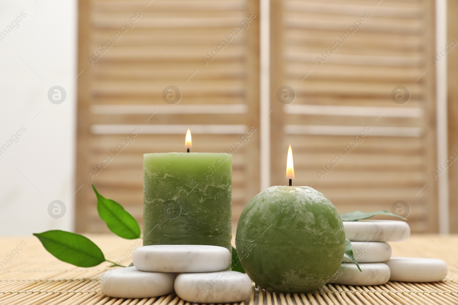 Photo of Composition with spa stones and candles on bamboo mat