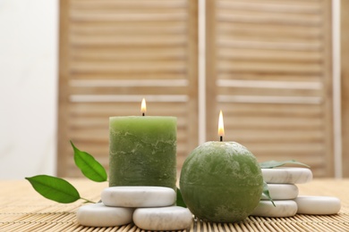 Composition with spa stones and candles on bamboo mat