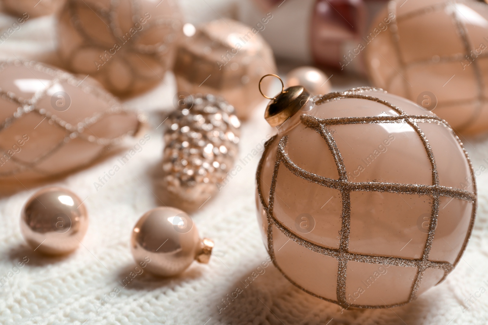 Photo of Beautiful Christmas tree baubles on white knitted fabric, closeup