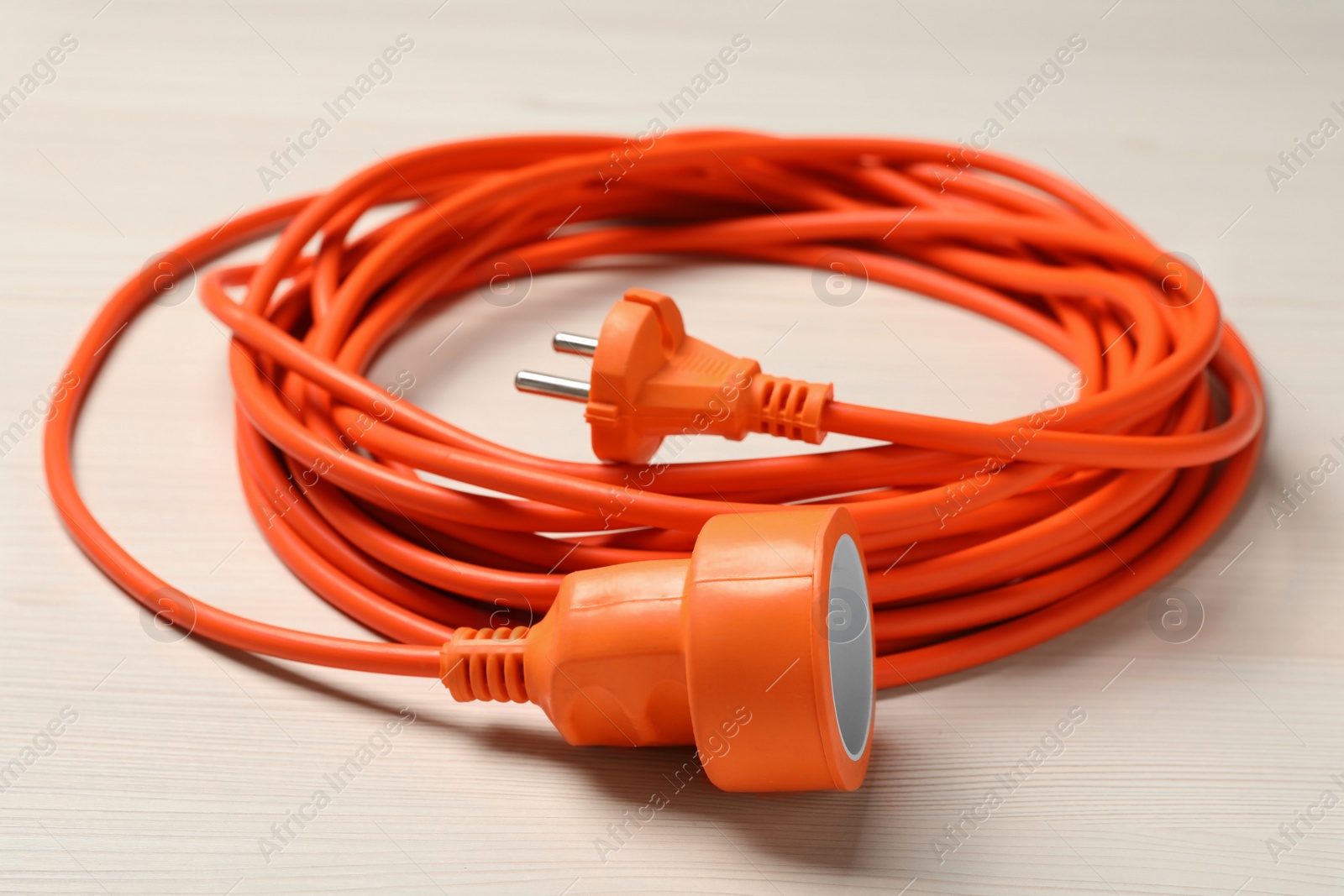 Photo of Extension cord on white wooden floor, closeup. Electrician's equipment