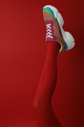 Photo of Woman wearing sneakers on red background, closeup
