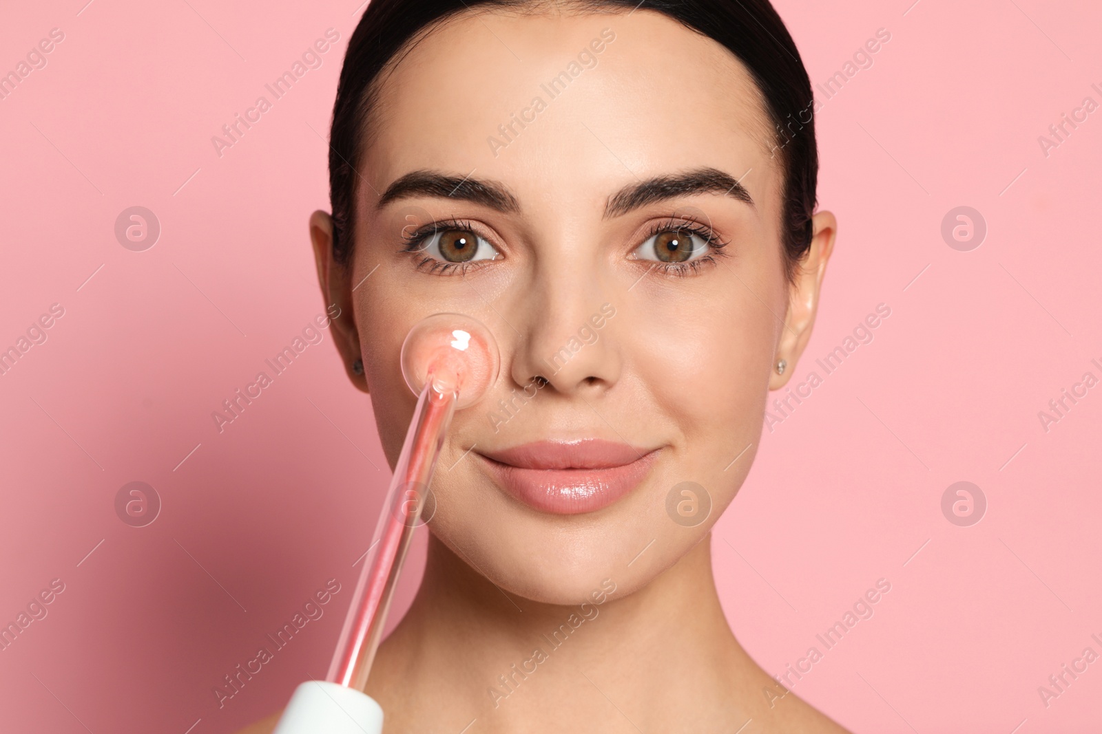 Photo of Woman using high frequency darsonval device on pink background