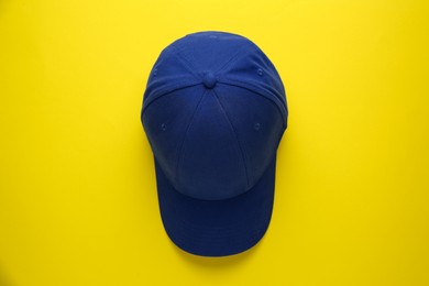 Photo of Stylish blue baseball cap on yellow background, top view