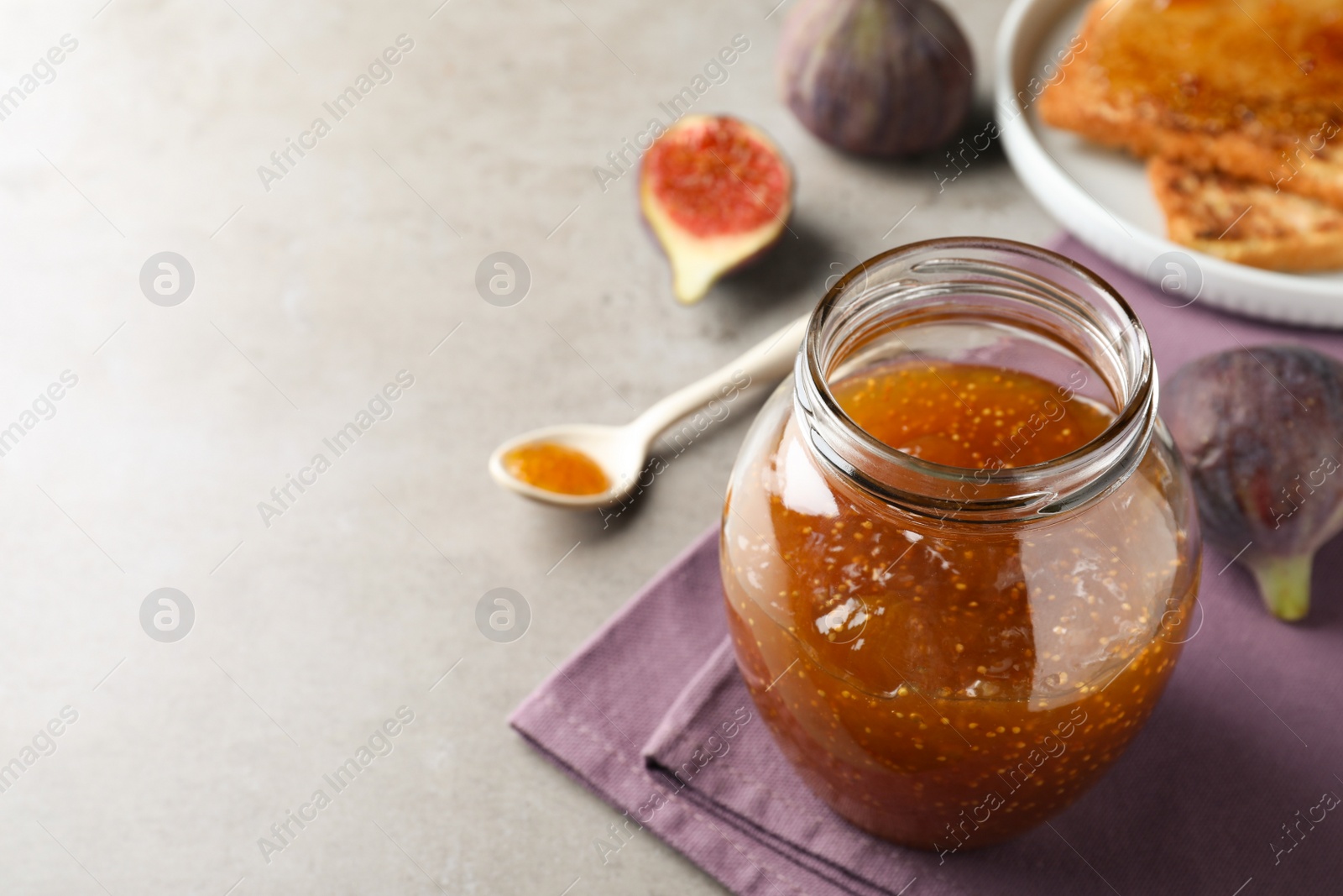 Photo of Delicious fig jam on grey table, closeup. Space for text