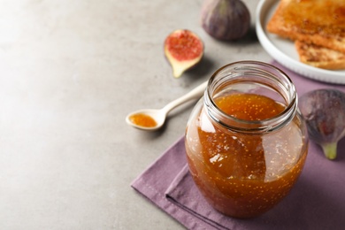 Photo of Delicious fig jam on grey table, closeup. Space for text