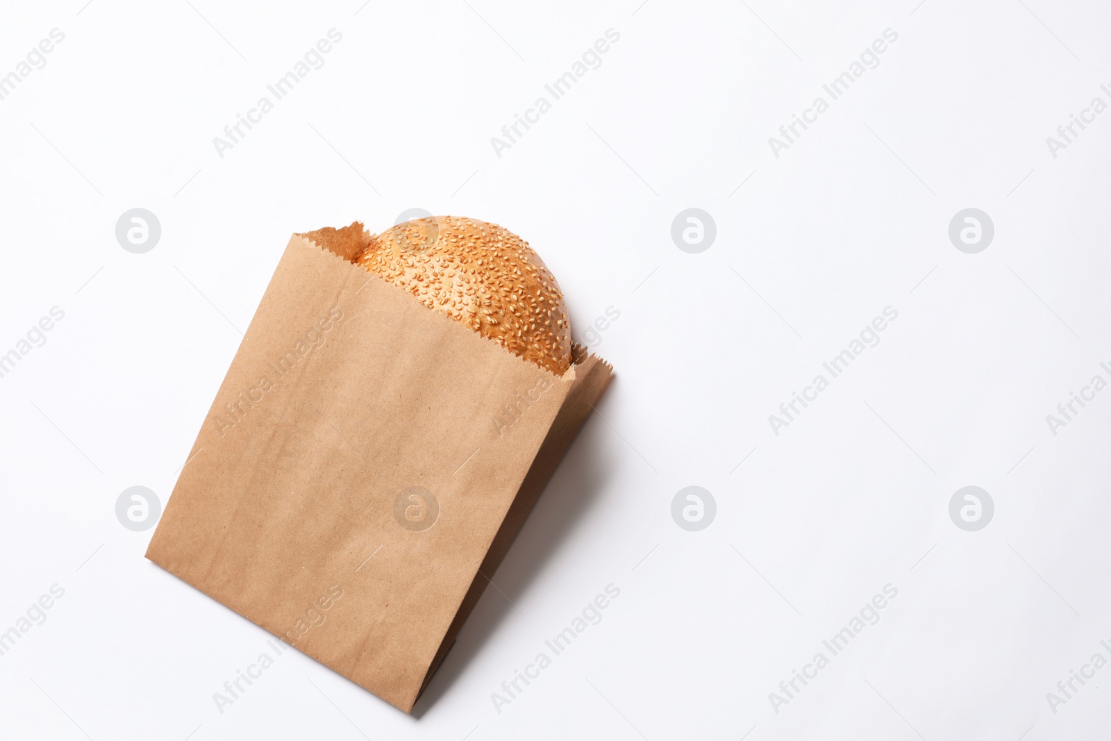 Photo of Paper bag with sesame bun on white background, top view. Space for text