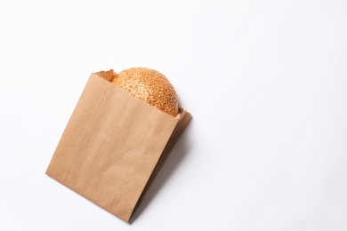 Photo of Paper bag with sesame bun on white background, top view. Space for text