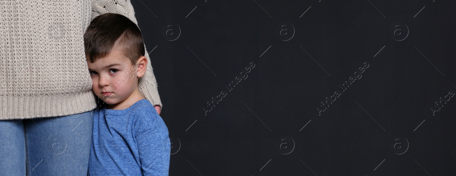 Image of Sad little boy hugging his mother on black background, banner design with space for text. Time to visit child psychologist