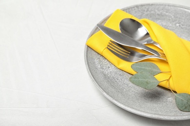 Photo of Plate with cutlery and napkin on light table, closeup. Space for text