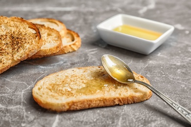 Toasted bread with honey on grey background