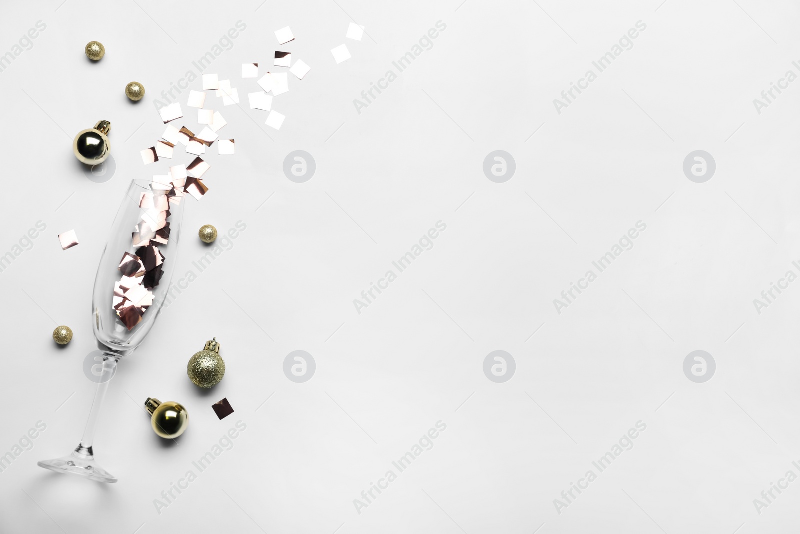 Photo of Flat lay composition with confetti, festive decor and champagne glass on light background. Space for text