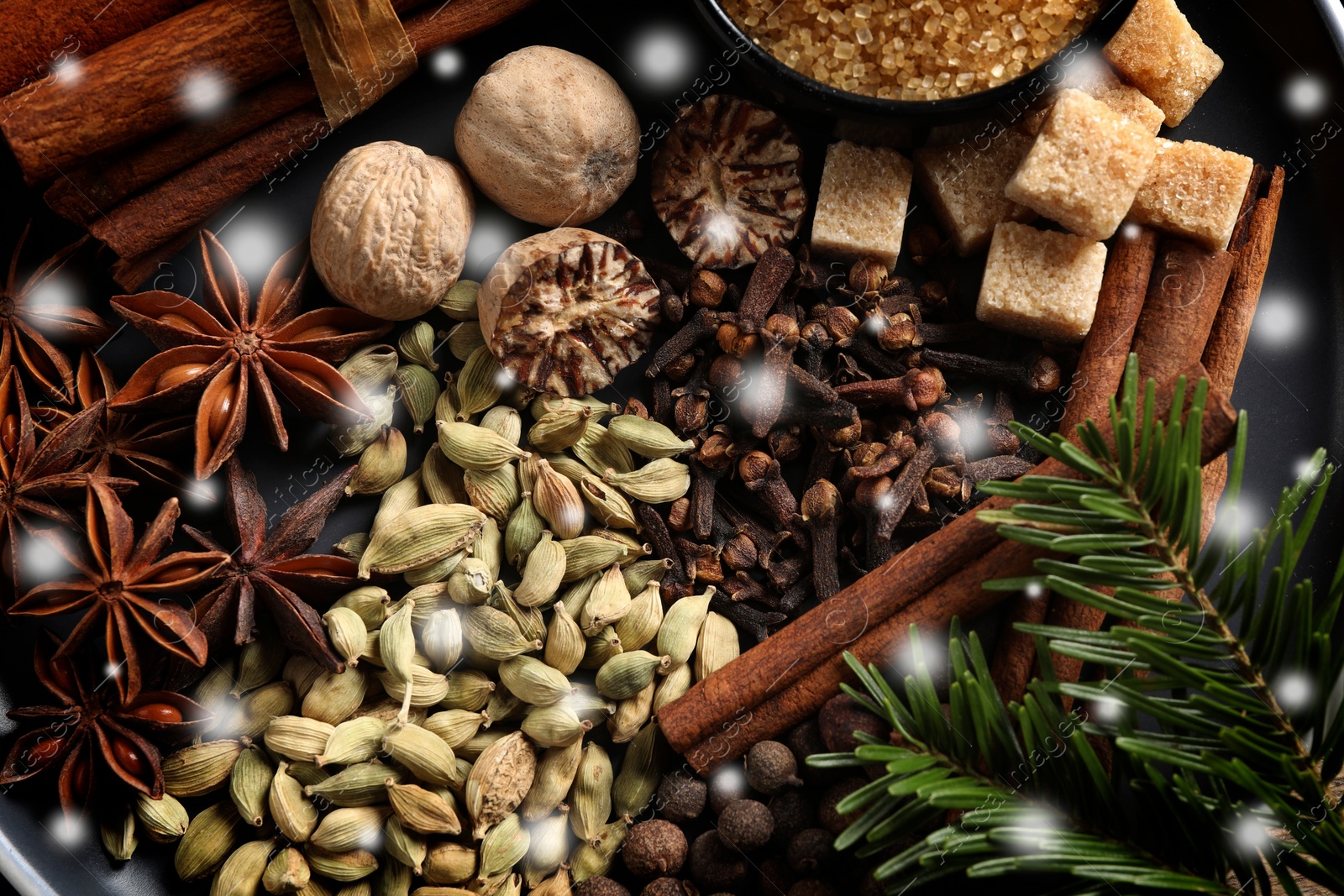 Image of Different spices and fir tree branches on black background, flat lay. Cinnamon, cloves, anise, cardamom, nutmegs, allspice