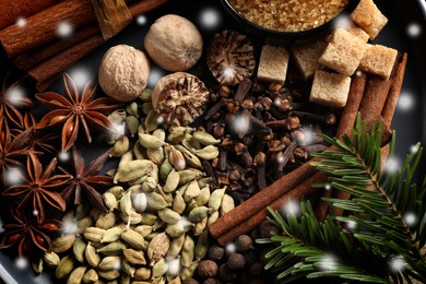 Different spices and fir tree branches on black background, flat lay. Cinnamon, cloves, anise, cardamom, nutmegs, allspice