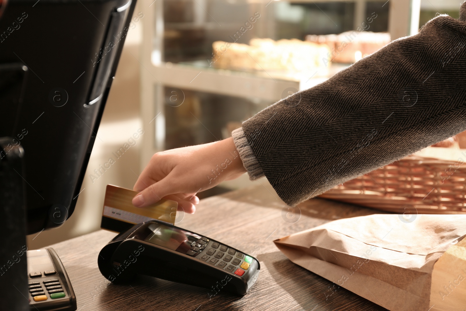 Photo of Woman with credit card using payment terminal at shop, closeup