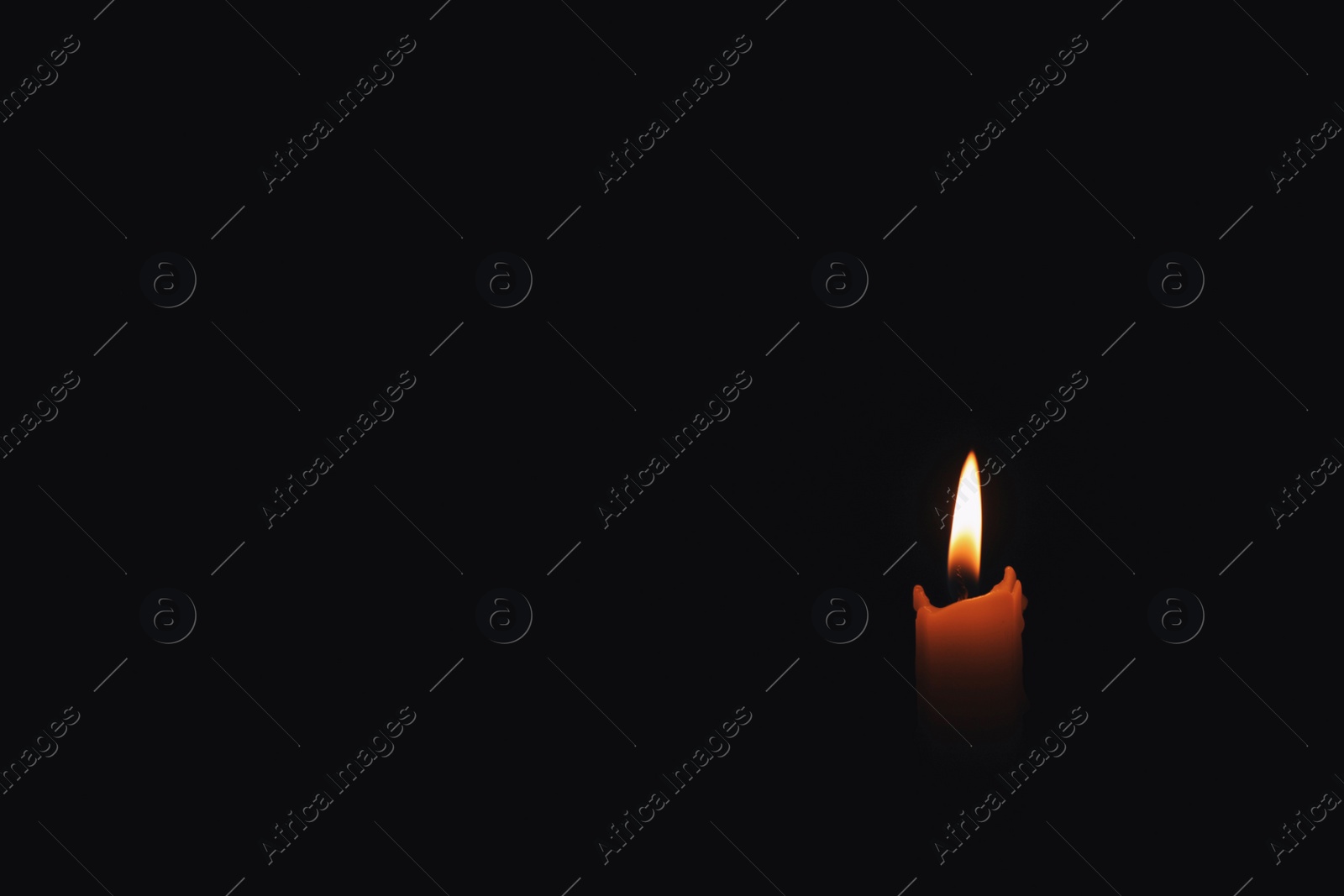 Photo of Burning wax candle in darkness. Space for text