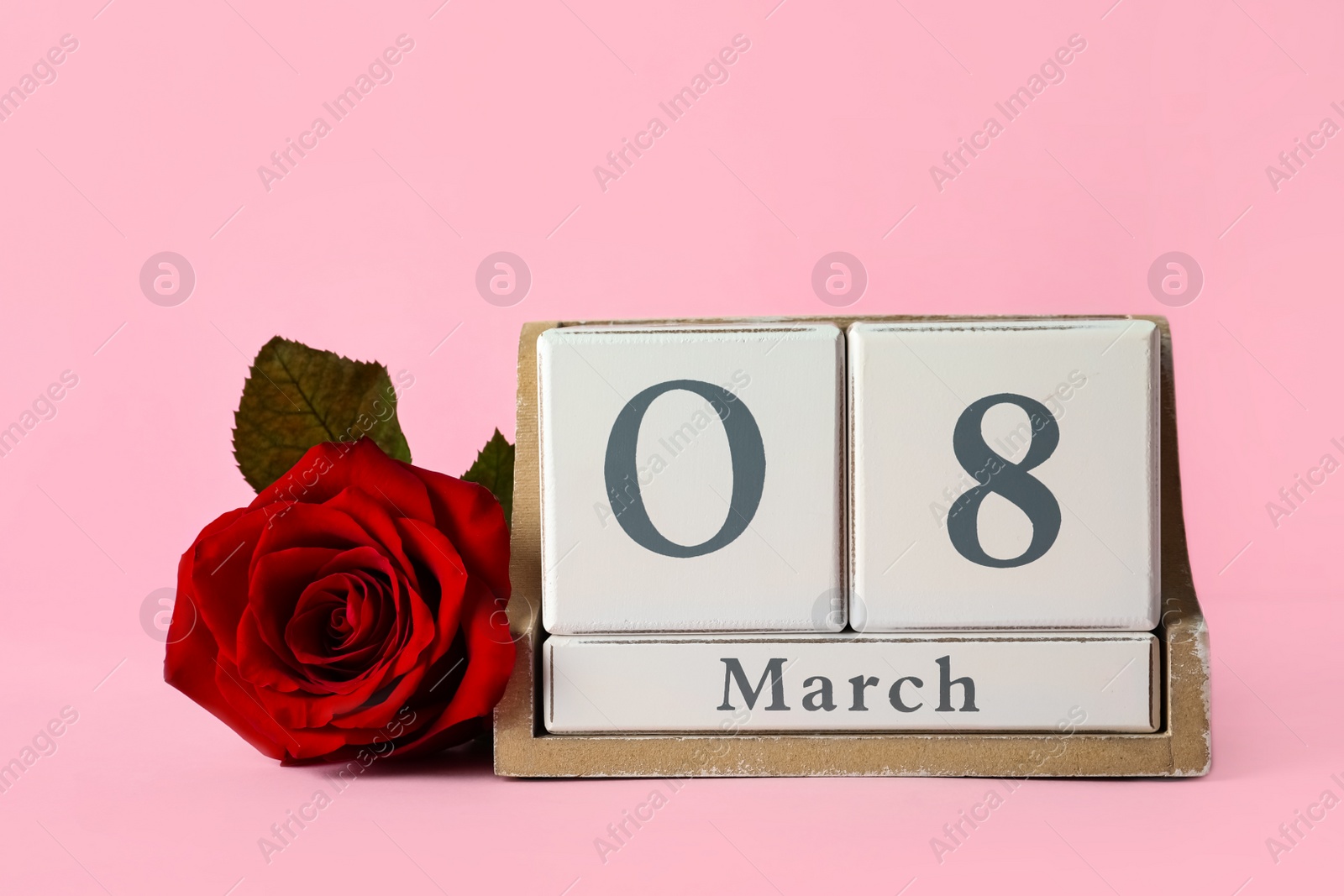 Photo of Wooden block calendar with date 8th of March and rose on pink background, space for text. International Women's Day