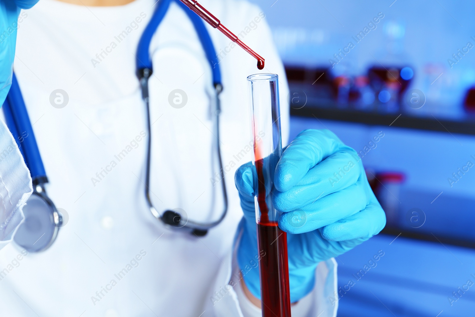 Photo of Laboratory worker pipetting blood sample into test tube for analysis, closeup