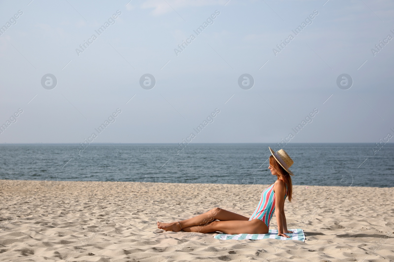 Photo of Woman with beach towel resting on sandy seashore, space for text