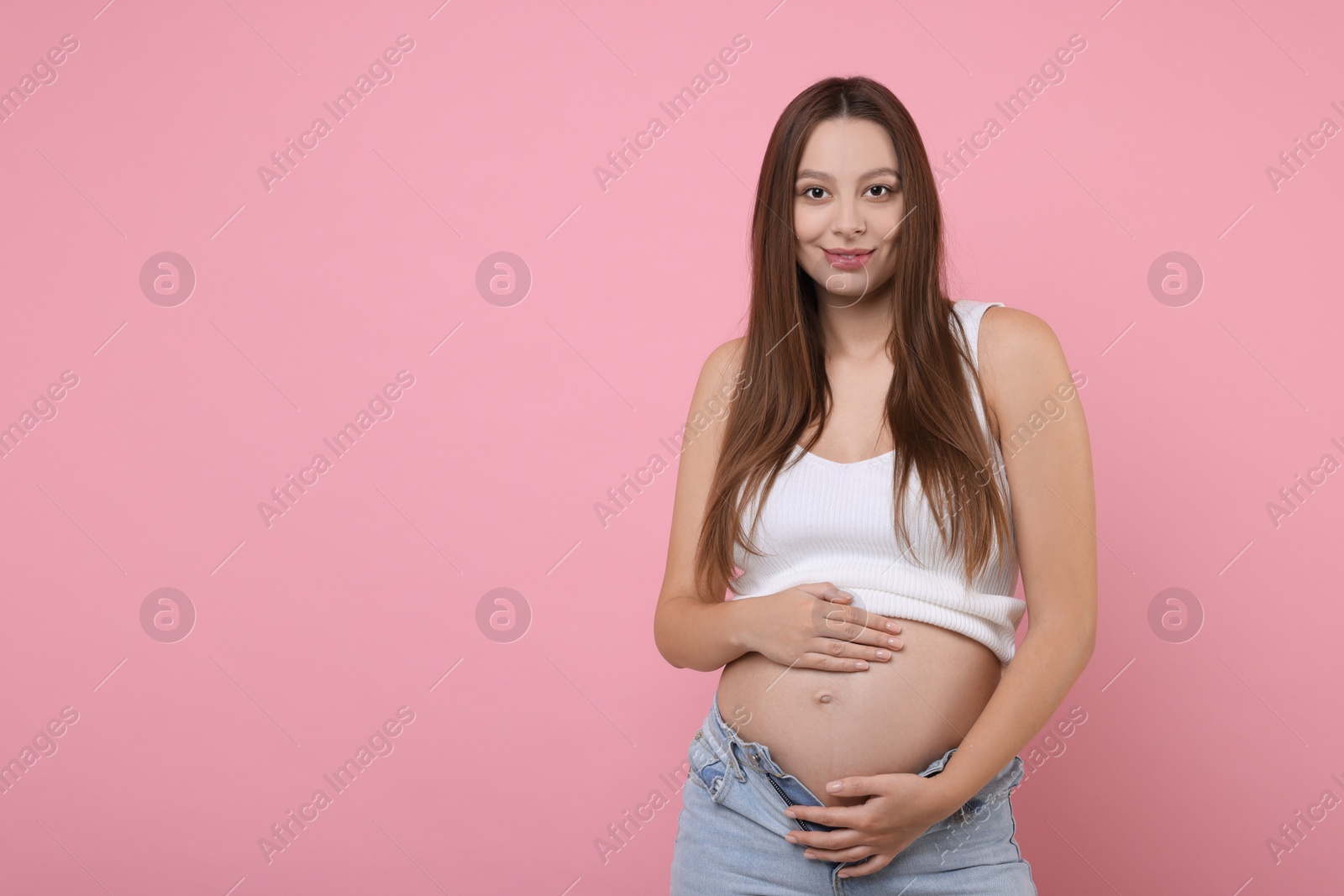 Photo of Beautiful pregnant woman with long hair on pink background, space for text