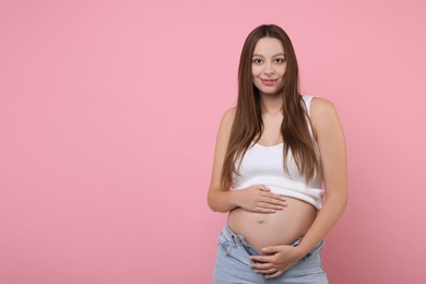 Photo of Beautiful pregnant woman with long hair on pink background, space for text