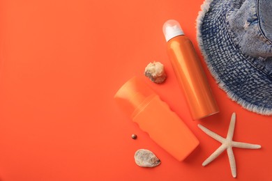 Photo of Flat lay composition with bottles of sunscreen on coral background. Space for text