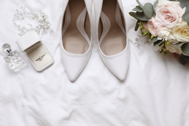 Flat lay composition with wedding high heel shoes on white fabric, space for text