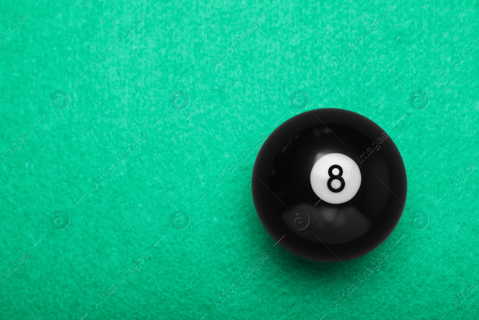 Photo of Billiard ball with number 8 on green table, top view. Space for text