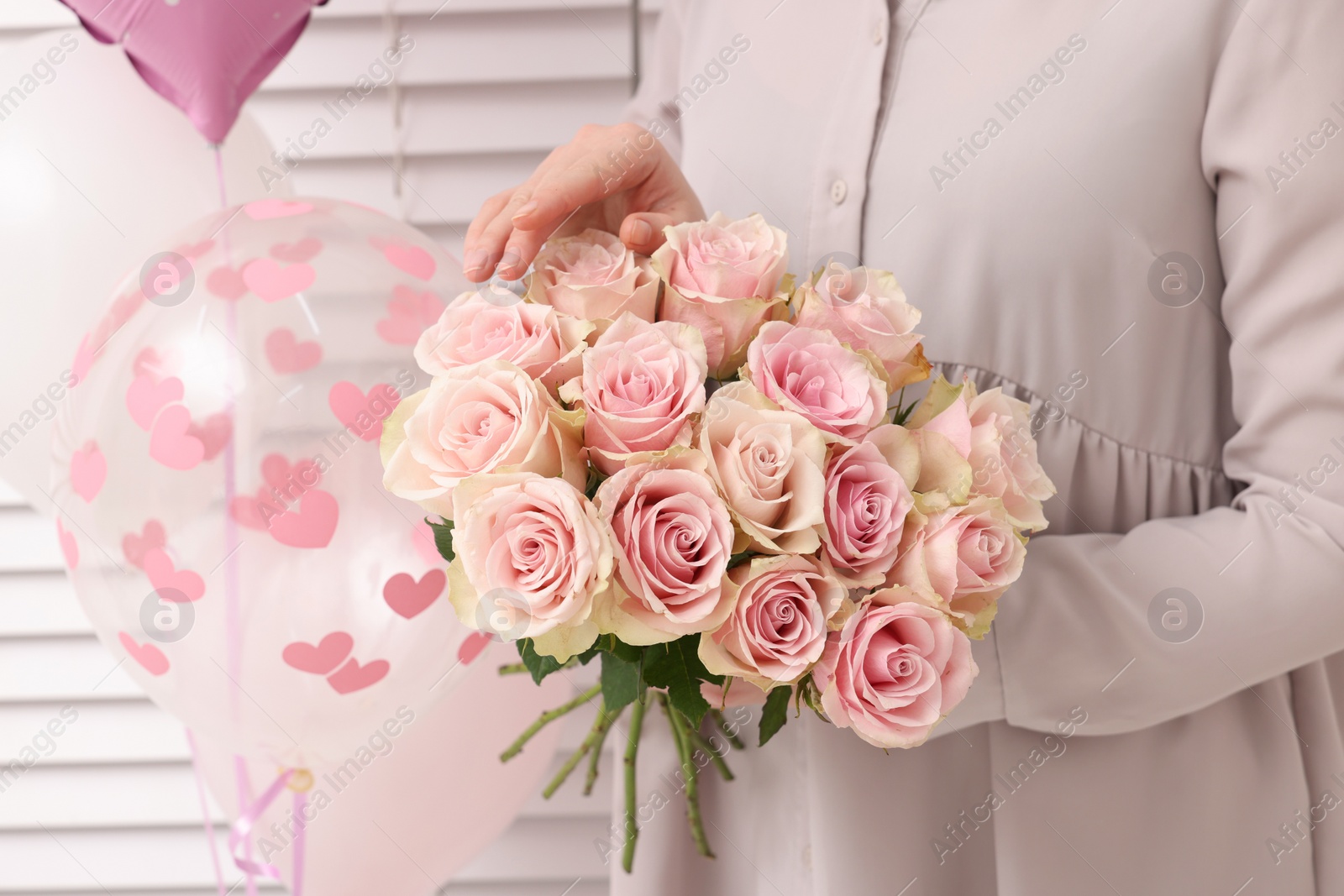 Photo of Woman holding bouquet of beautiful rose flowers near air balloons indoors, closeup. Happy birthday