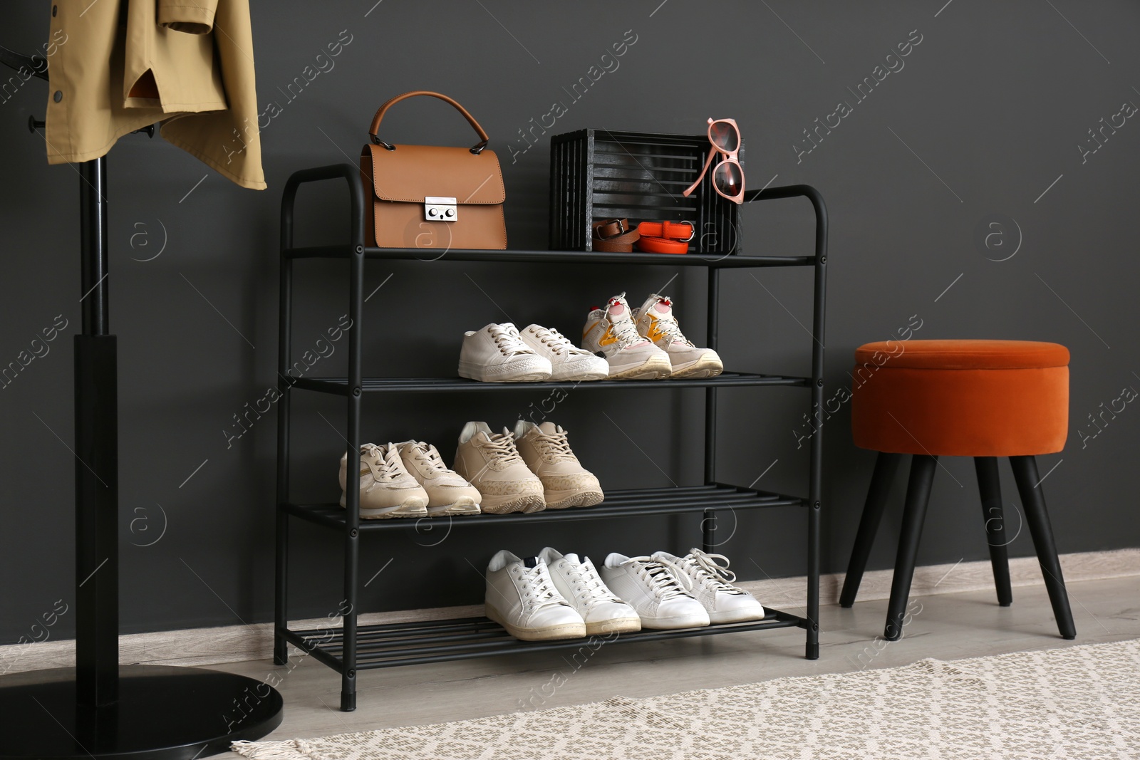 Photo of Shelving rack with stylish shoes and accessories near black wall at home. Idea for hallway interior design