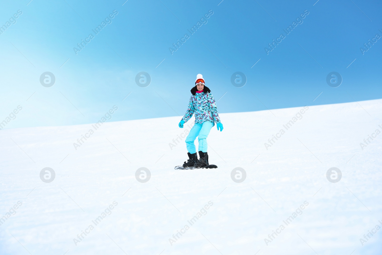 Photo of Young woman snowboarding on hill at mountain resort. Winter vacation