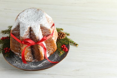 Photo of Delicious Pandoro cake with powdered sugar and red bow, Christmas decor on white wooden table, above view with space for text. Traditional Italian pastry