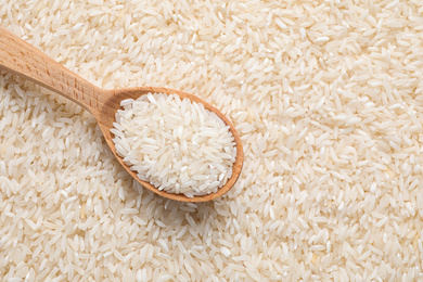 Photo of Pile of polished rice and wooden spoon, top view