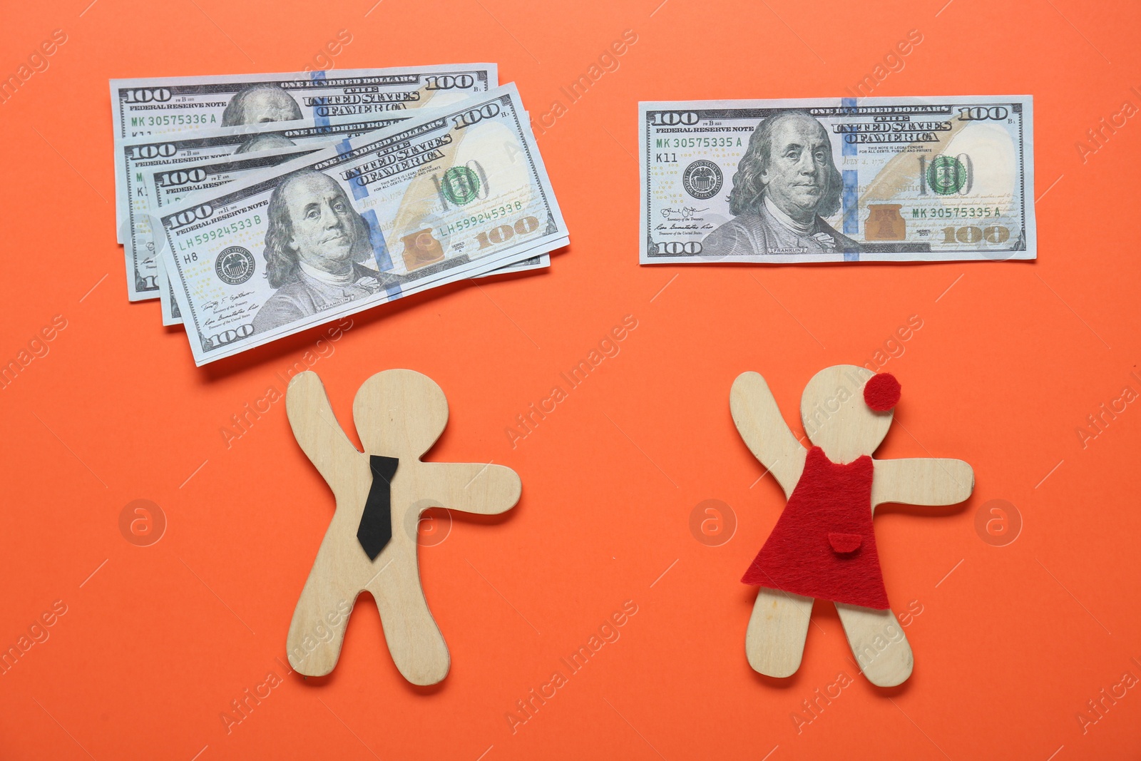 Photo of Gender pay gap. Wooden figures of man and woman with banknotes on orange background, flat lay