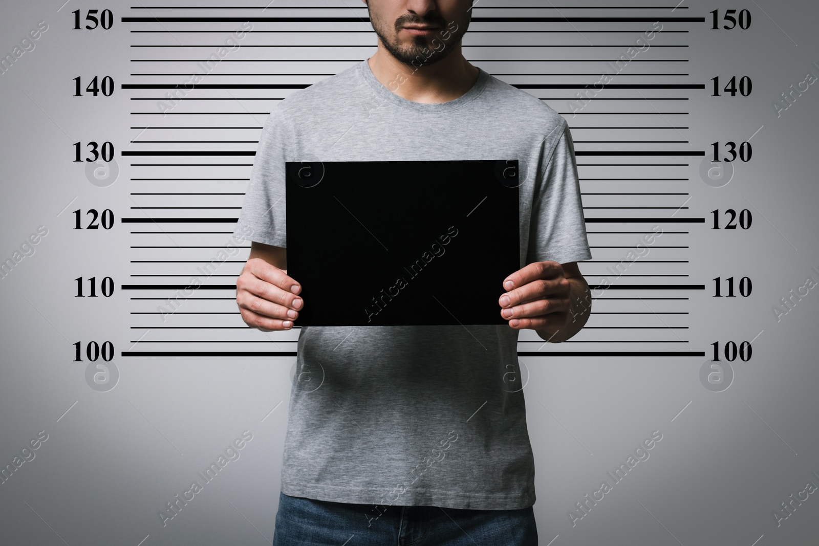 Image of Criminal mugshot. Arrested man with blank card against height chart, closeup