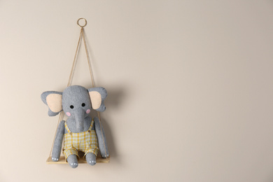 Photo of Shelf with cute toy elephant on beige wall, space for text. Child's room interior element