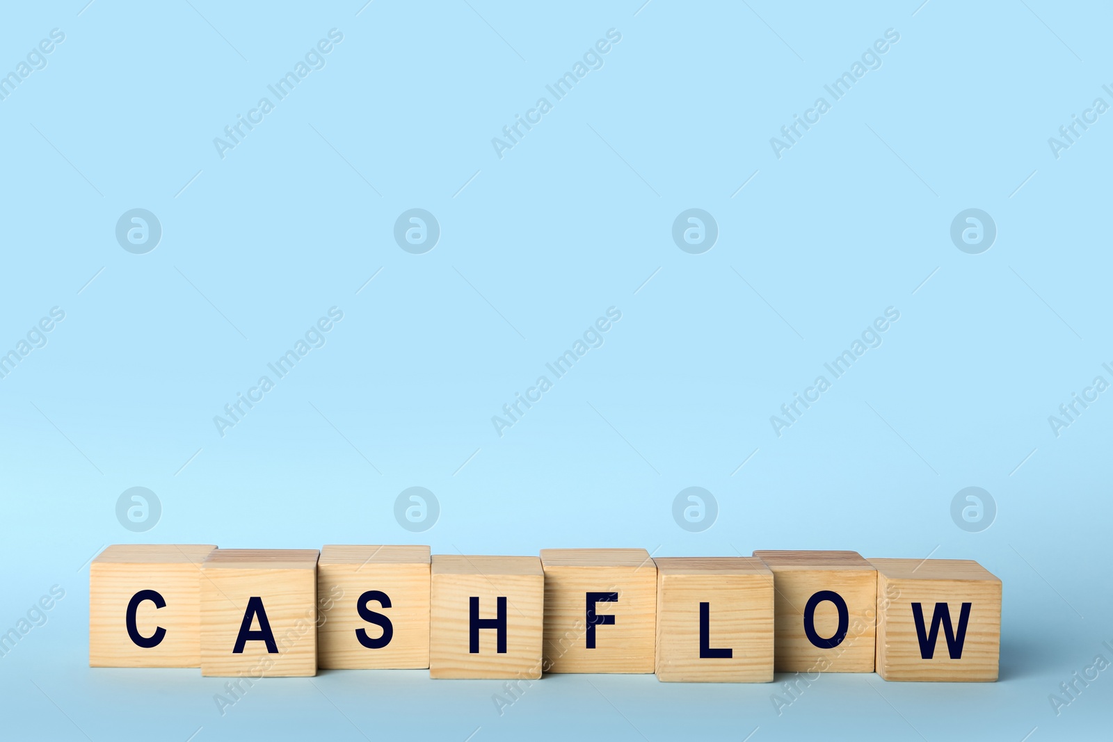 Image of Wooden cubes with phrase Cash FLow on light blue background. Space for text