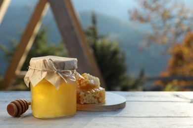 Photo of Fresh aromatic honey and combs on grey wooden table outdoors. Space for text