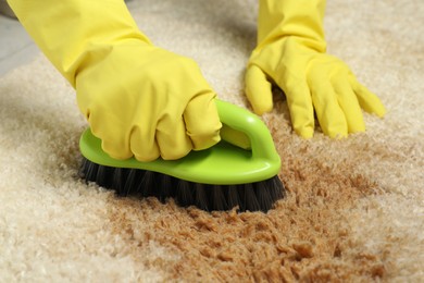 Woman removing stain from beige carpet, closeup