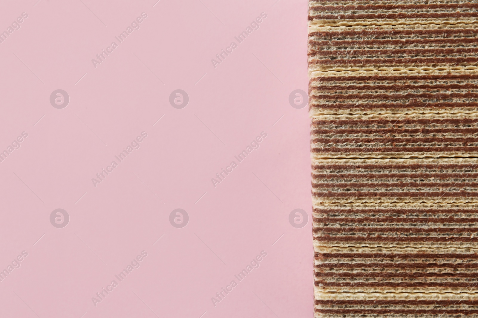 Photo of Tasty wafer sticks on pink background, flat lay with space for text. Sweet food