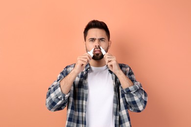 Photo of Man using nasal sprays on peach background