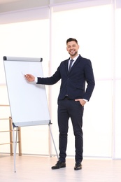 Young business trainer near flip chart, indoors