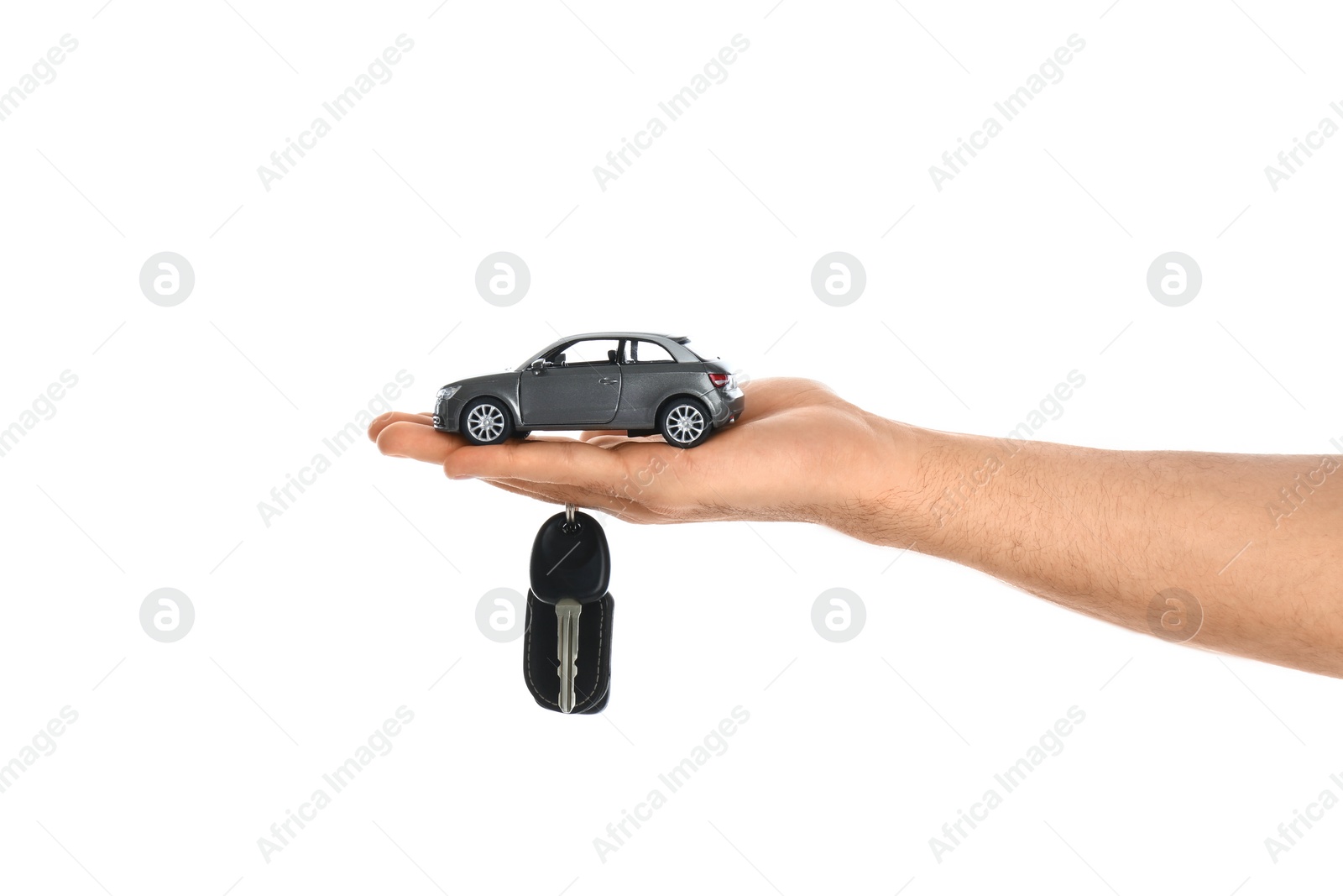 Photo of Man holding key and miniature automobile model on white background, closeup. Car buying