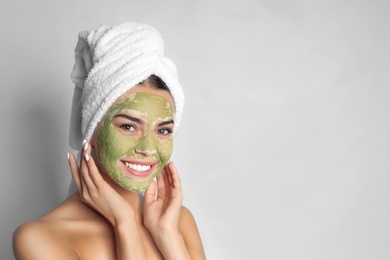 Young woman with clay mask on her face against light background, space for text. Skin care