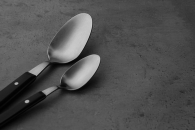 Photo of Clean empty table spoons on grey background, space for text