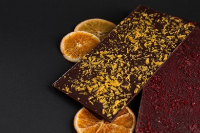 Chocolate bars with freeze dried fruits on black background, space for text